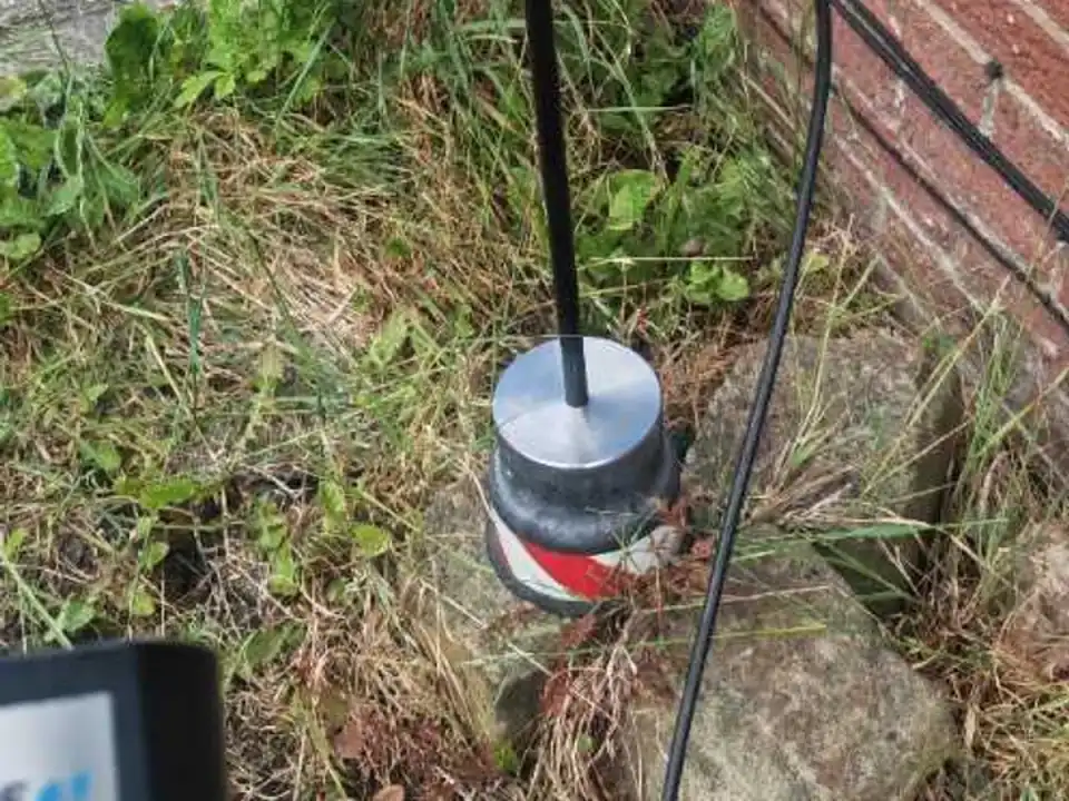 Tracer gas probe placed in front garden soil during leak detection survey