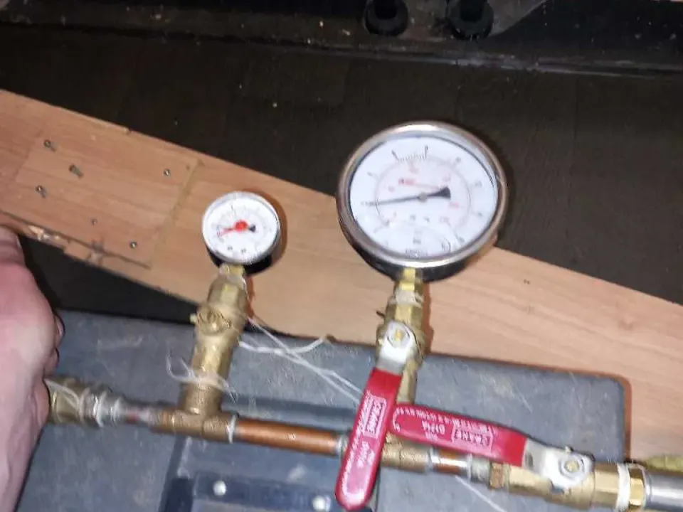 Dual-gauge pressure testing rig connected to kitchen cold mains pipework during leak detection