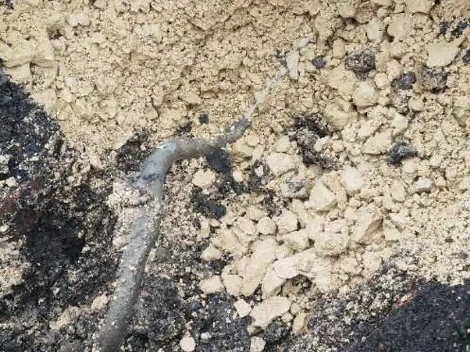 Leak located beneath excavated tarmac patch in courtyard revealing sandy subsoil