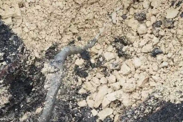 Leak located beneath excavated tarmac patch in courtyard revealing sandy subsoil