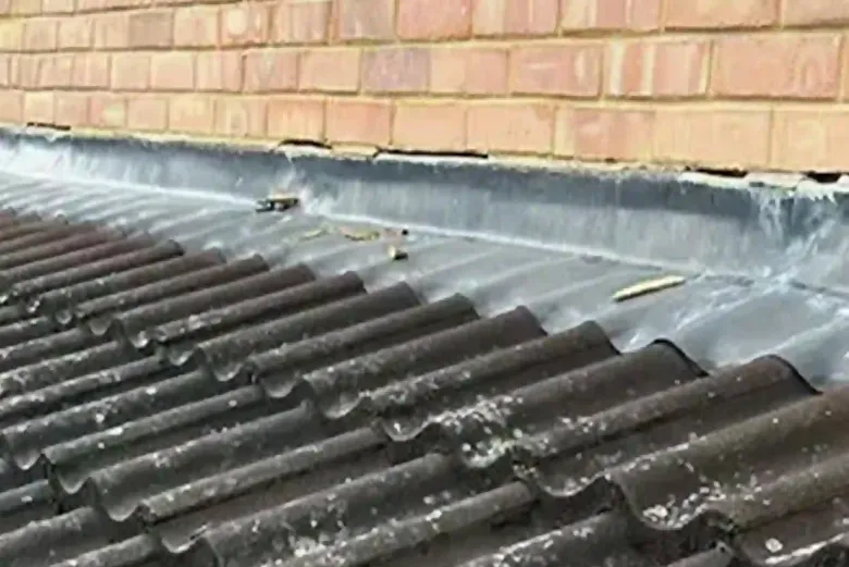 Pitched roof tiles and lead flashing against a brick wall